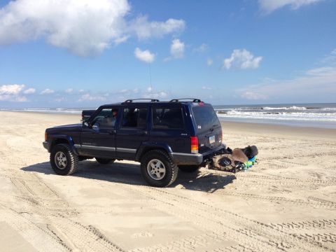 1979 Ford Bronco - Jeep Cherokee XJ on the beach, likely from the late 1990s or early 2000s.