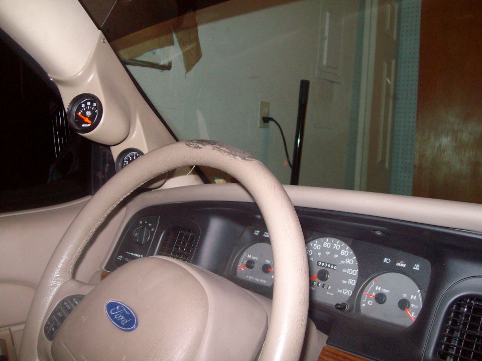 Ford steering wheel, dashboard, and aftermarket gauges mounted on the A-pillar