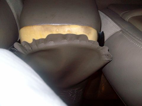 2004 Ford Crown Victoria - Interior detail showing tan upholstery with exposed yellow foam padding behind a trim panel.
