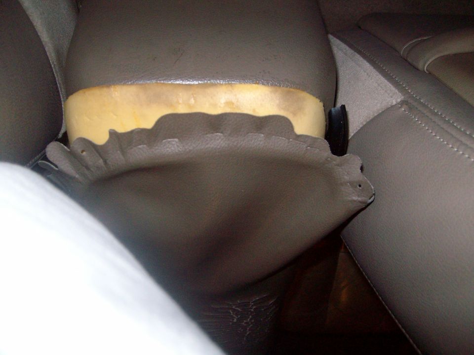 Tan vehicle interior detail with yellow foam padding behind upholstered panel