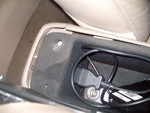2004 Ford Crown Victoria - A close-up view of a car's center console storage area, showing a diagnostic cable and power outlet.