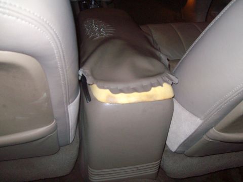 2004 Ford Crown Victoria - The torn center console shows exposed foam, contrasting with the surrounding tan leather interior.