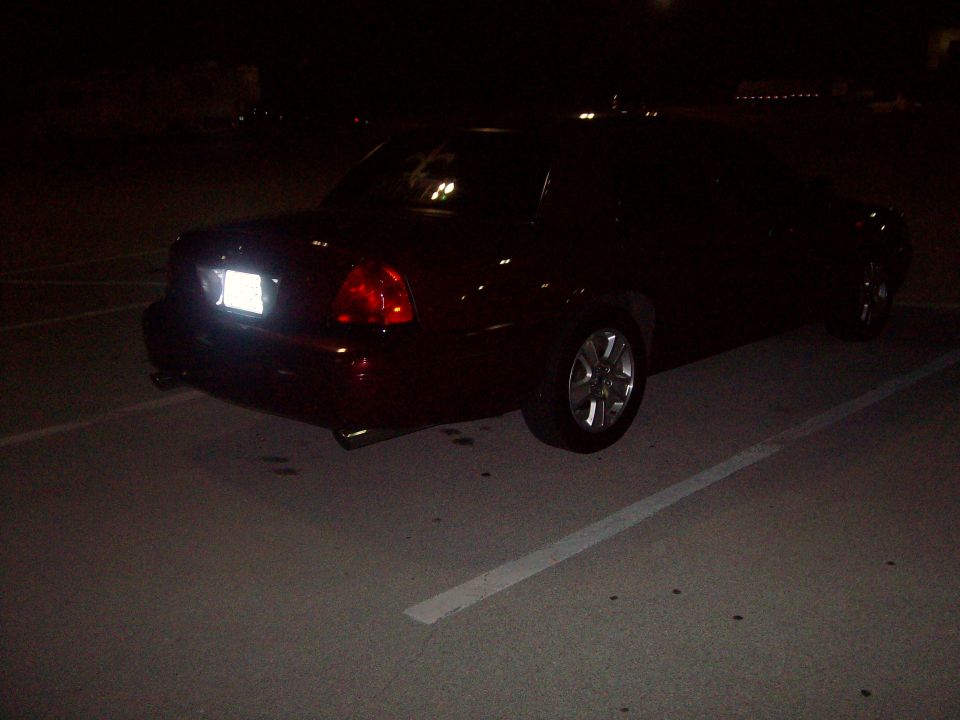 Dark sedan's rear view at night, showing taillights and license plate area