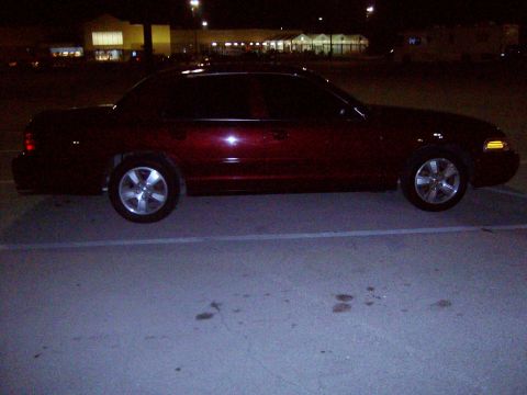 2004 Ford Crown Victoria - Maroon sedan parked in a lot at night. The body style suggests a Ford Crown Victoria, likely from the 2003 model year.