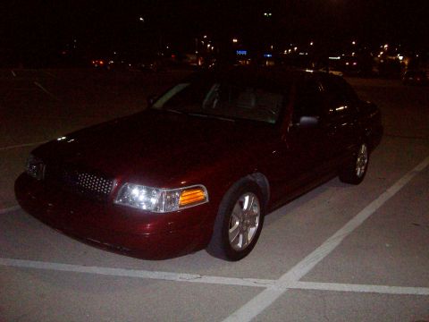 2004 Ford Crown Victoria - A dark red sedan is parked in a lot at night, showing its front 3/4 view.