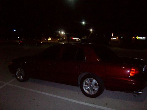 2004 Ford Crown Victoria - A dark red 2004 Ford Crown Victoria is parked in a lot at night, showing its side profile.