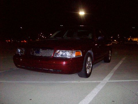 2004 Ford Crown Victoria - A dark red 2004 Ford Crown Victoria is parked at night, showing its front and side profile.