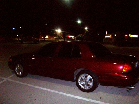 2004 Ford Crown Victoria - Side profile of a red 2004 Ford Crown Victoria parked in a lot at night.