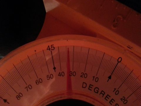 1995 Ford Bronco - A close-up of an orange angle gauge with markings for degrees.