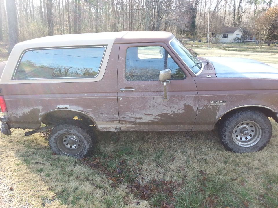 Brown 1991 Ford Bronco side view. Mud splattered