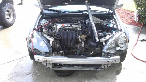 1994 Ford Bronco - The front bumper has been removed from this vehicle, exposing the engine and various mechanical components within the engine bay.