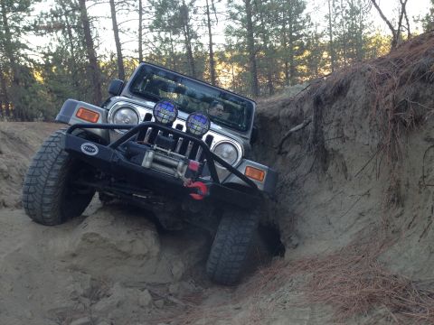 2005 Jeep Wrangler - A Jeep Wrangler navigates a challenging off-road trail, climbing a steep dirt incline.