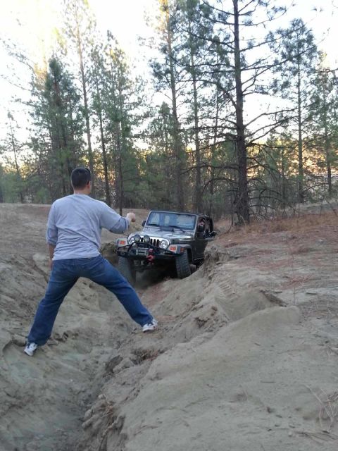 2005 Jeep Wrangler - Off-roading in a 2005 Jeep Wrangler on a dirt trail with a person watching.