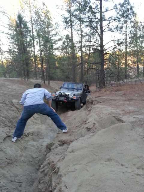2005 Jeep Wrangler - A person helps guide a Jeep Wrangler as it navigates a challenging off-road trail.