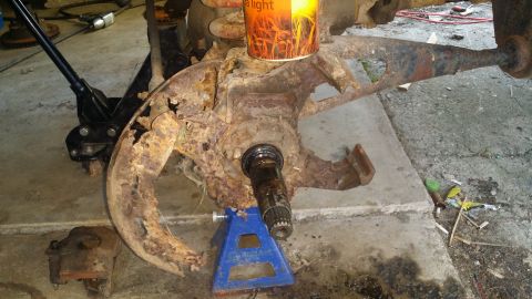 1983 Ford Bronco - Heavily rusted vehicle suspension component on a jack stand.