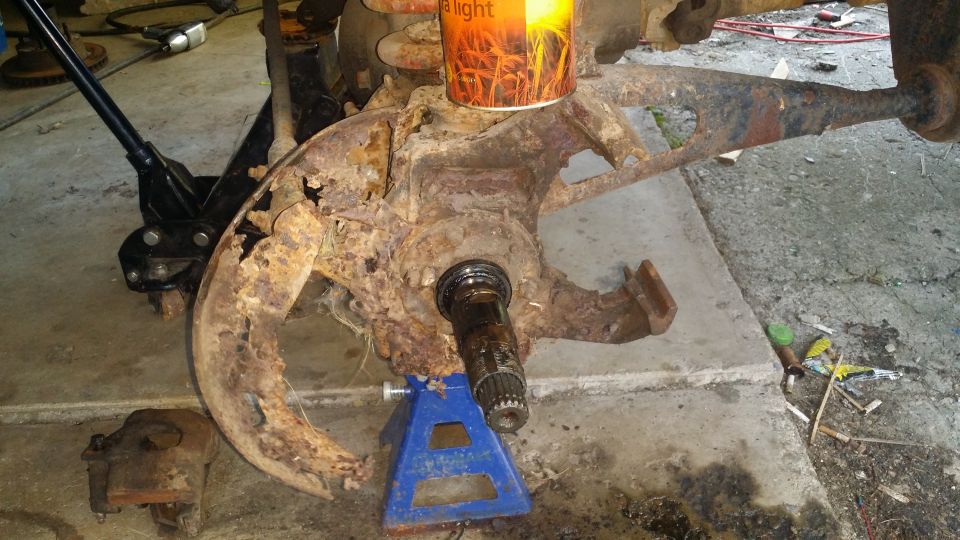 Heavily rusted vehicle suspension component supported by a jack and jack stand