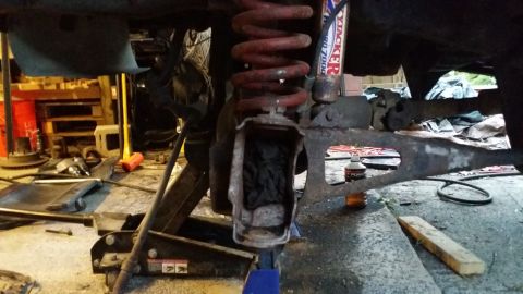 1983 Ford Bronco - A close-up view of a vehicle's suspension system, showing a red coil spring and a shock absorber with visible text.