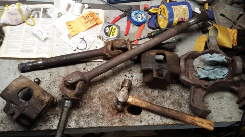 1983 Ford Bronco - Various automotive parts and tools are scattered across a cluttered workbench.