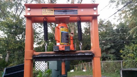 1983 Ford Bronco - A hydraulic shop press with a bottle jack is shown outdoors.