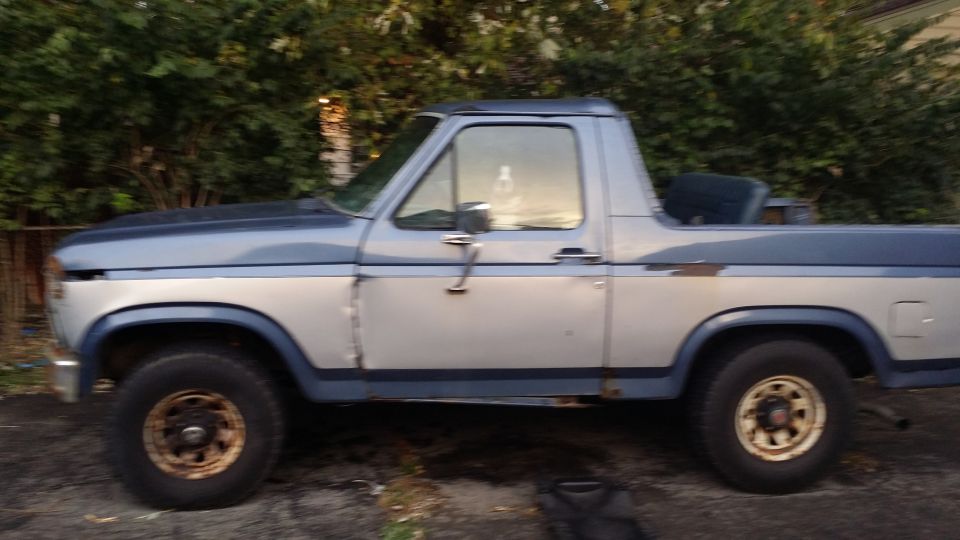 Side view of a two-tone blue and silver Ford Bronco with some rust