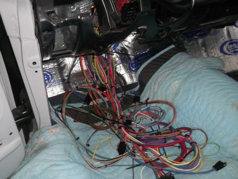 1967 Ford Mustang - A complex wiring harness is visible inside a vehicle, with sound deadening material on the floor and firewall.