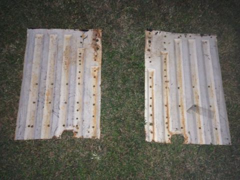 1979 Ford Bronco - Two rusty metal floor pans are laid out on the grass.