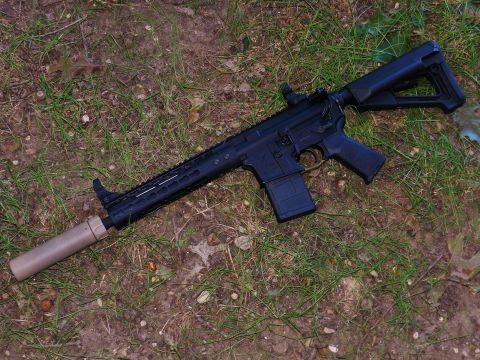 1996 Ford Bronco - A tactical rifle with a suppressor is placed on the grass and dirt.