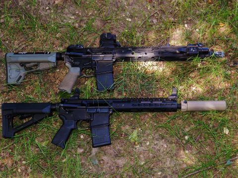 1996 Ford Bronco - Two assault rifles are displayed on a grassy surface, one equipped with a suppressor.