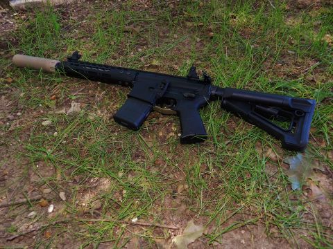 1996 Ford Bronco - An assault rifle with a suppressor and adjustable stock is visible on the ground, resting on grass and dirt.