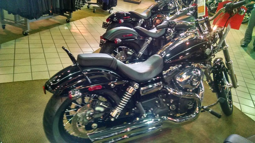Two black motorcycles parked indoors, one in the foreground showing its rear wheel and seat