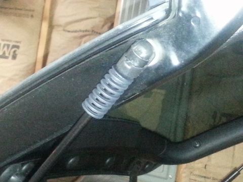 2010 MINI Cooper - A close-up view of the hood latch mechanism, showing the spring and connecting rod.