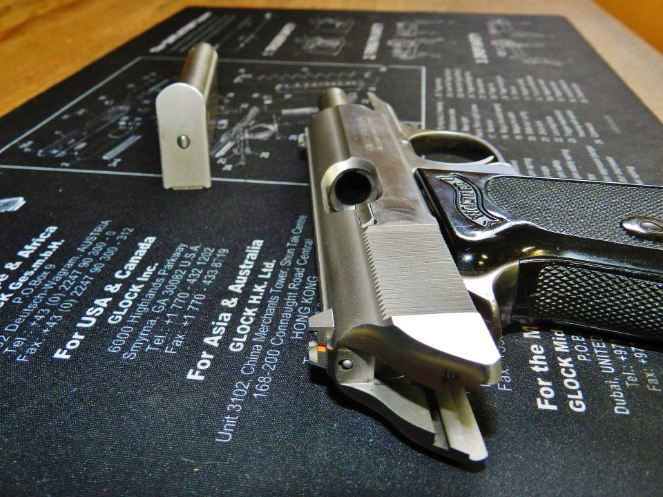 Pistol disassembled with magazine on a gun cleaning mat with Glock contact information