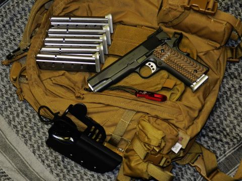 1996 Ford Bronco - A pistol, multiple magazines, a holster, and a multi-tool are laid out on a tan backpack.