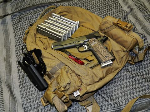 1996 Ford Bronco - A Springfield RO 1911 9mm pistol, several loaded magazines, and a holster are arranged on a tan tactical backpack.