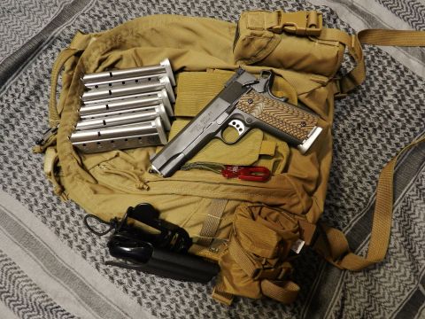 1996 Ford Bronco - A close-up view of a handgun, multiple magazines, and tactical gear arranged on a patterned fabric background.
