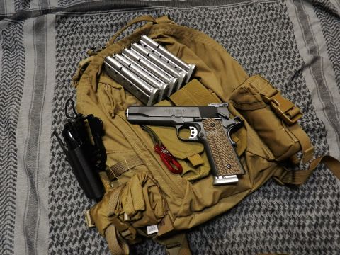 1996 Ford Bronco - A pistol, magazines, and holster are laid out on a tan backpack and patterned cloth.