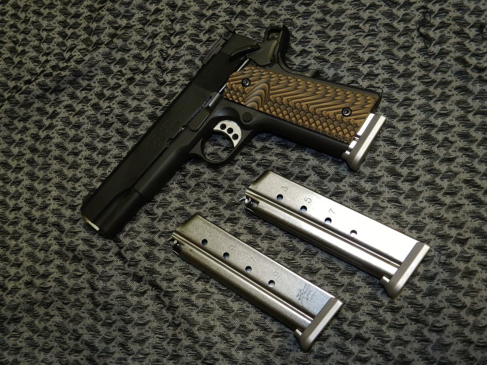 Pistol with textured grip and two magazines on patterned surface