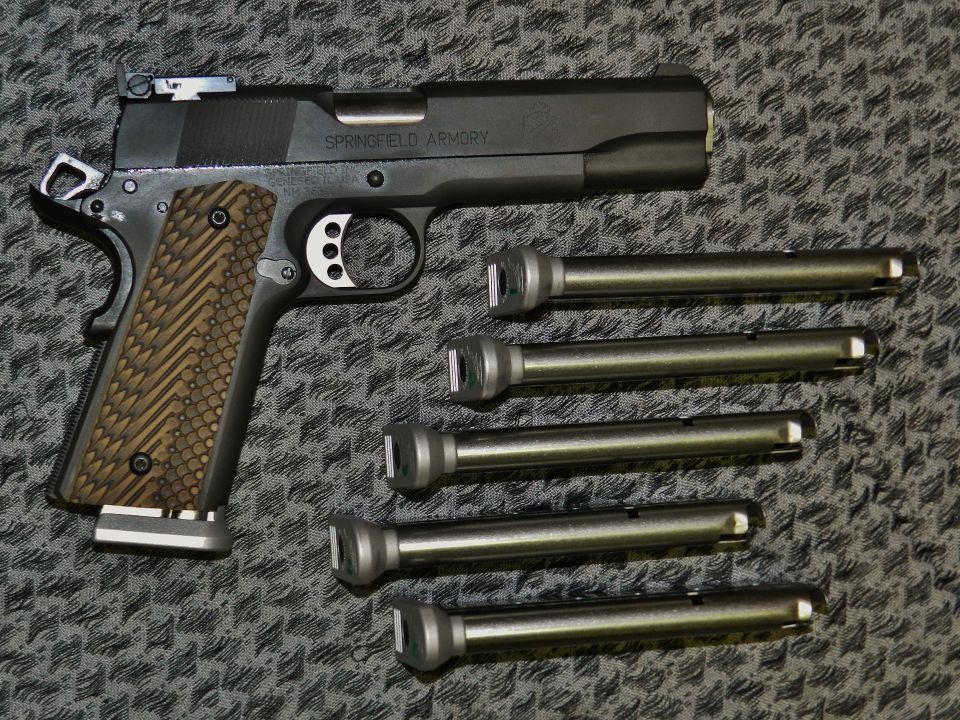 Springfield Armory pistol with five extra barrels laid out on a patterned surface