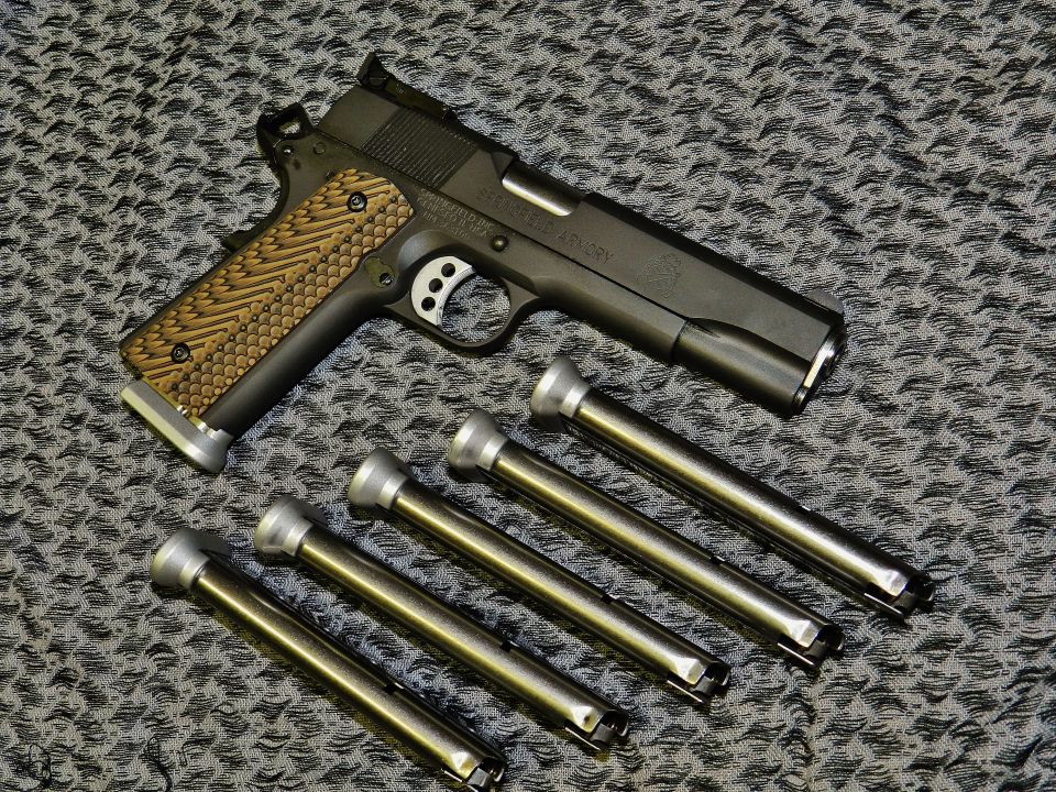 Black Springfield RO 1911 9mm pistol with textured grip and four magazines on a patterned surface