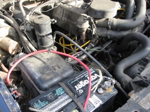 1985 Ford Bronco - The engine compartment contains a battery and various hoses and wiring, with a visible "SUPERMOTORS.NET" watermark.