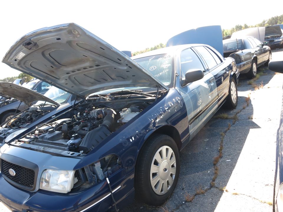 2001 Ford Crown Victoria with hood open, showing engine bay. Another car is parked behind it