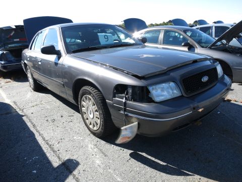 2001 Ford Crown Victoria - Front view of a grey 2001 Ford Crown Victoria, showing damage to the front passenger side light assembly.