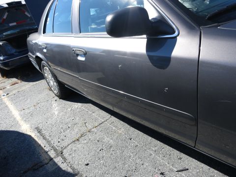 2001 Ford Crown Victoria - A dark gray sedan is parked on asphalt, with another vehicle's trunk open in the background.