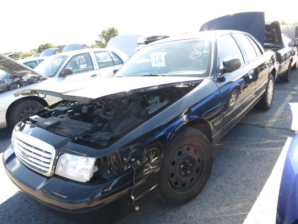 Black Ford Crown Victoria with hood open, parked in a lot with other cars