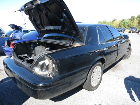 2001 Ford Crown Victoria - A black 2001 Ford Crown Victoria is seen with its trunk open and a missing taillight, parked next to another vehicle.