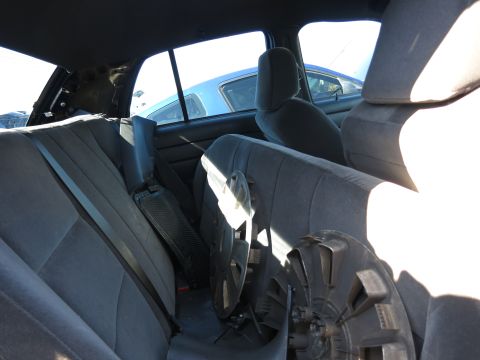 2001 Ford Crown Victoria - The interior of a car shows grey seats and spare parts on the floor, with another vehicle visible through the window.