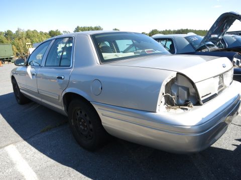 2001 Ford Crown Victoria - Silver 2001 Ford Crown Victoria seen from the rear quarter with damage to the taillight area.