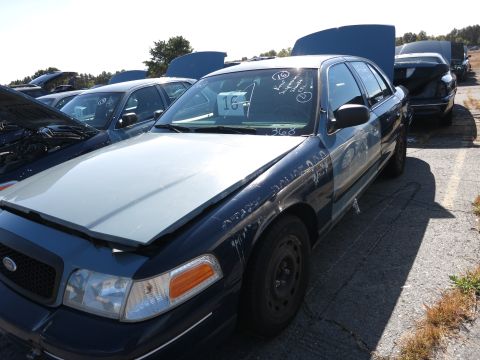 2001 Ford Crown Victoria - A fleet of Ford Crown Victorias are parked with hoods up in an outdoor lot.