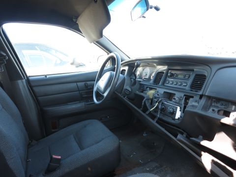 2001 Ford Crown Victoria - The interior of a 2001 Ford Crown Victoria police car is shown, with the dashboard and driver's seat visible.