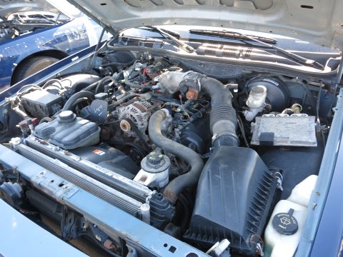 2001 Ford Crown Victoria - The engine bay of a 2001 Ford Crown Victoria is shown, with another blue vehicle visible in the background.